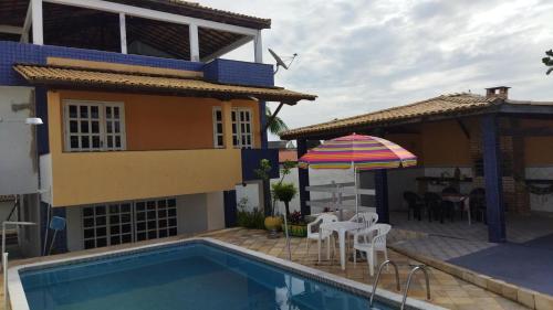 a house with a swimming pool and an umbrella at Diversão, churrasco e piscina - Praia de Ipitanga in Salvador
