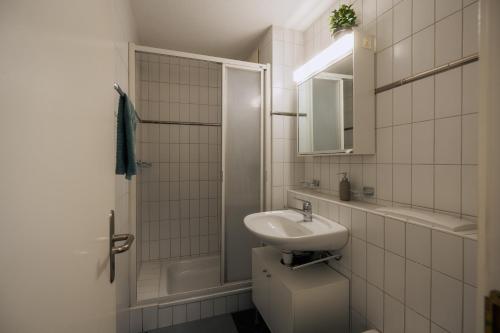 ein weißes Bad mit einem Waschbecken und einer Dusche in der Unterkunft Gemütliches Studio im Stadtzentrum in Biel