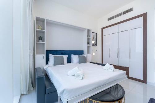 1 dormitorio con 1 cama blanca grande y toallas. en Lovely Studio with View of Dubai Miracle Garden en Dubái