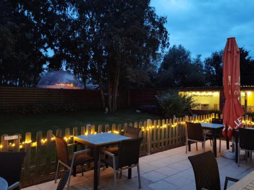 a patio with tables and chairs and a fence with lights at Glamping UNIVERSE in Ettelgem