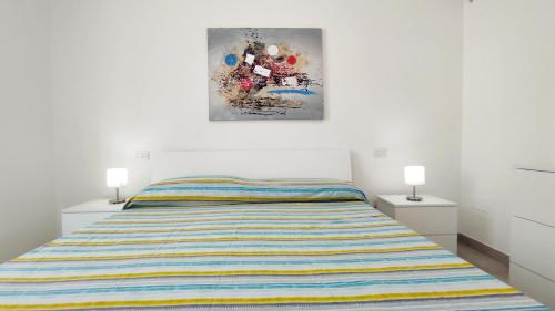 1 dormitorio con 1 cama y una pintura en la pared en Le Sorelle del Mare - Sole e Persia, en Marina di Pescoluse