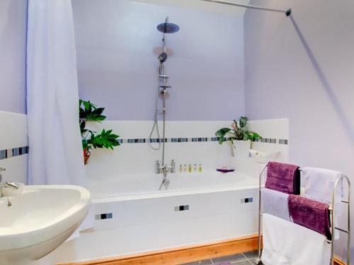 a bathroom with a white tub and a sink at Lily Rose Cottage in Gilsland