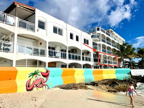 a woman walking on the beach in front of a building at Maho Beach House - Spacious 2 Bedroom - Ocean View in Maho Reef