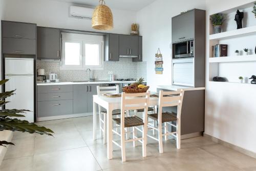 eine Küche mit grauen Schränken sowie einem weißen Tisch und Stühlen in der Unterkunft Chic & Spacious House in Rodia Heraklion in Iraklio