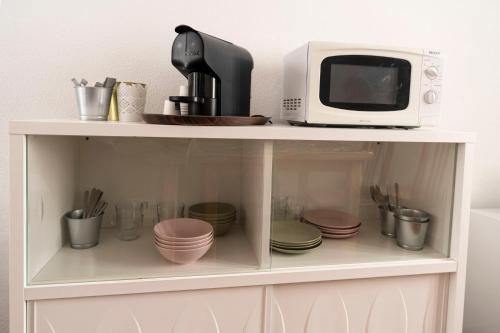 a white cabinet with a microwave and dishes on it at D'Iberica Alojamento in Évora