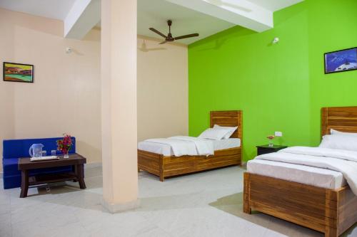 two beds in a room with a green wall at Rains Inn Eco Hotel in Diphu