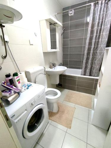 a bathroom with a washing machine and a toilet at Nota Home in Novi Sad