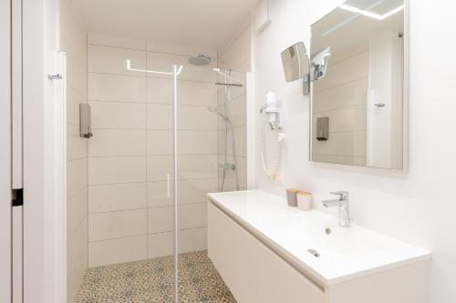een witte badkamer met een wastafel en een douche bij B&B Tabibito in Genk