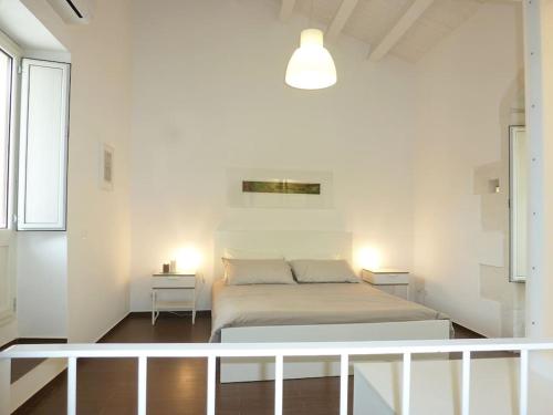een witte slaapkamer met een bed en 2 tafels bij Dimora d'Artista in Ragusa