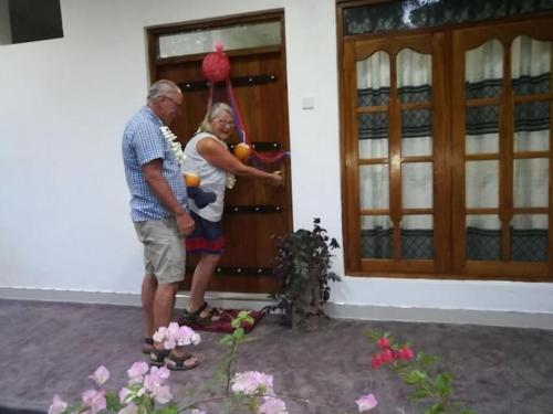 a man and a woman standing outside of a house at Turtle Paradise in Tangalle