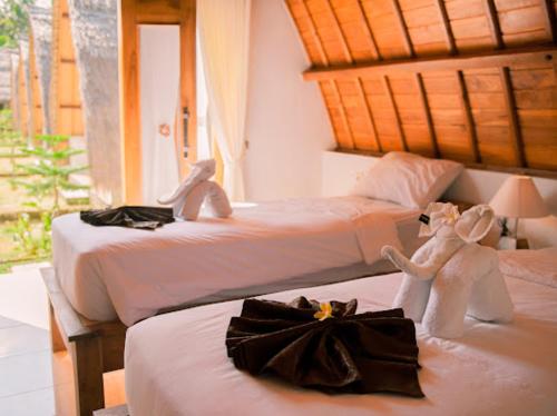 duas camas num quarto com bichos de peluche em Lempeh Jungle Cottage em Nusa Penida
