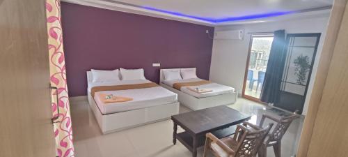 Cette petite chambre comprend deux lits et une table. dans l'établissement Hotel Greenvalley Residency, à Punalūr