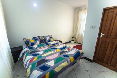 - une chambre avec un lit et une couette colorée dans l'établissement Melvis' place, à Dar es Salaam
