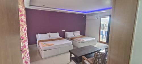 Cette petite chambre comprend deux lits et une table. dans l'établissement Hotel Greenvalley Residency, à Punalūr