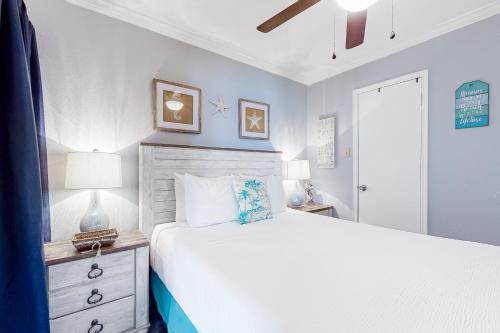 a bedroom with a white bed and a nightstand and a bed sidx sidx sidx at Victorian Condo #9312 in Galveston