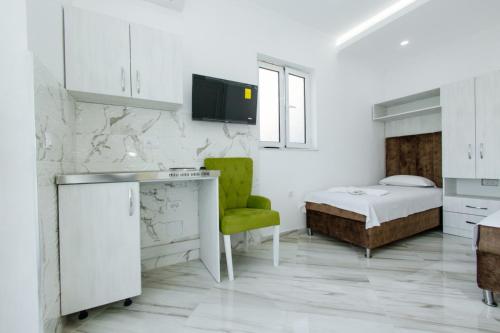 a white bedroom with a bed and a green chair at Flori Apartments in Ulcinj