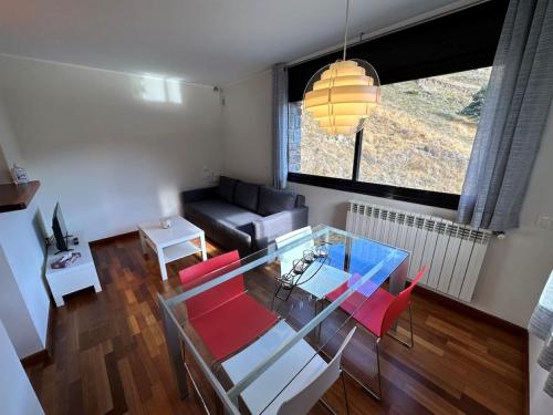uma sala de estar com uma mesa de vidro e cadeiras vermelhas em Apartament Narcis 2.5 - 5p - Ransol - Zona Grandvalira em El Tarter