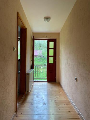 an empty hallway with a red door and a wooden floor at Family owned self sufficient ECO farm TARA in Pljevlja