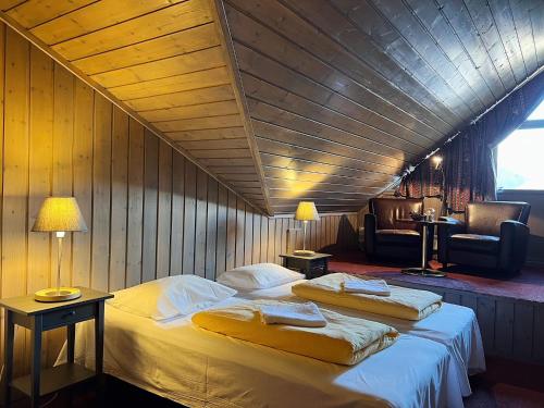 a bedroom with two beds and a chair in a room at Fanitullen Hotel in Hemsedal