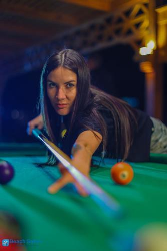 a woman is playing pool on a pool table at Beach safari nubian resort in Marsa Alam City