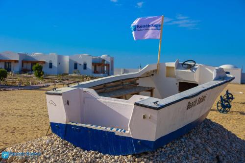 a boat on the beach with a flag on it at Beach safari nubian resort in Marsa Alam City