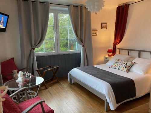 1 dormitorio con cama, mesa y ventana en L'Araucaria - chambres d'hôtes et gîte en Ploërdut