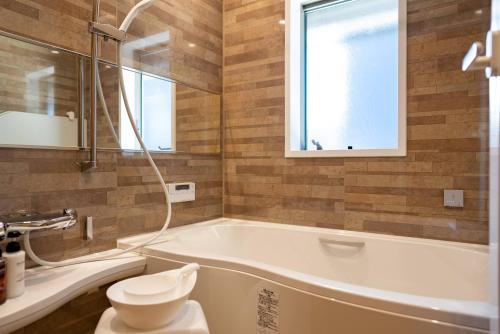 a bathroom with a tub and a toilet and a window at IZA近江舞子 in Minami-komatsu