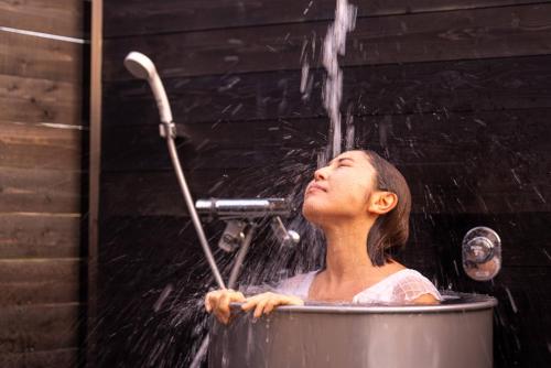 a woman is taking a bath in a pot of water at IZA近江舞子 in Minami-komatsu