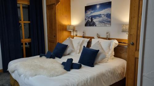 a bedroom with a bed with blue and white pillows at Arc 1950 Appartement de standing Refuge du Montagnard, vue incroyable sur le Montblanc, skis aux pieds Accès spa et piscine in Arc 1950