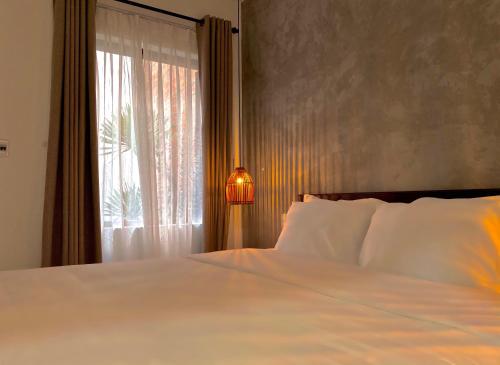 a bedroom with a white bed and a window at Okra Hoian in Hoi An