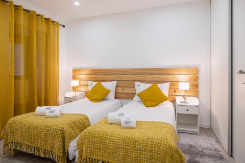 two beds in a hotel room with yellow pillows at Casa de Santa Catarina - Ponta Delgada in Ponta Delgada