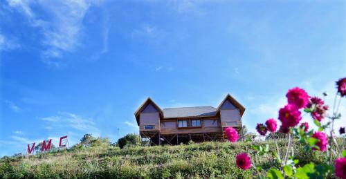 a house on top of a hill with pink flowers at Vrindhavan Farm Suites in Kanthalloor