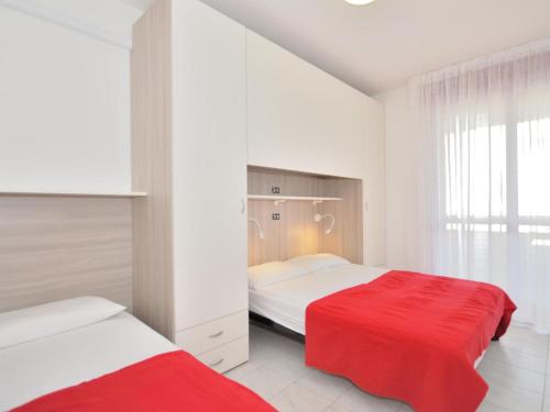 una camera con due letti e una coperta rossa di Modern two-room apartment Condominio Nautilus Bibione a Bibione