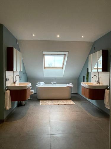 a bathroom with two sinks and a tub and a window at Bonne Suite Chambre d'Hotes in Rekem