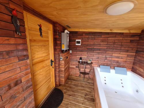 a bath tub in a room with a wooden wall at Domos Trayenko in Ralún