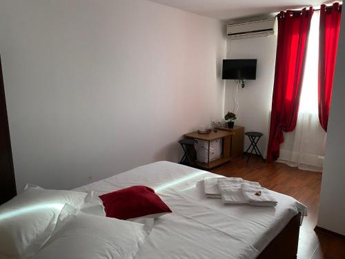 a bedroom with a white bed with red curtains at La Olteanu in Brăila