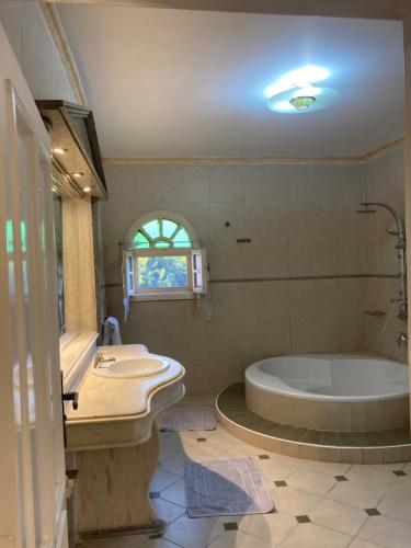 a bathroom with a tub and a sink at Al Fardous Luxury Vacation Home in King Mariout