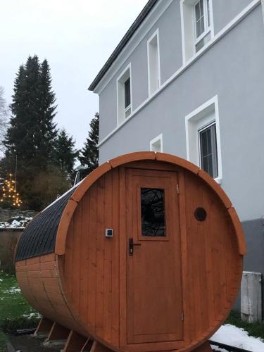 a wooden barrel with a door in front of a house at Mein Eifel Ferienhaus Altes Pfarrhaus in Dahlem