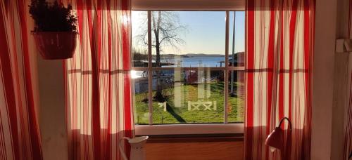 una ventana con cortinas rojas y blancas en una habitación en Uusi Saunamökki Jämsässä, lähellä Himosta, en Jämsä