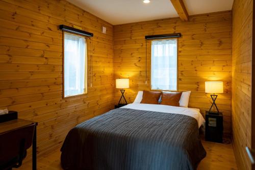 a bedroom with wooden walls and a bed with two lamps at IZA近江舞子 in Minami-komatsu