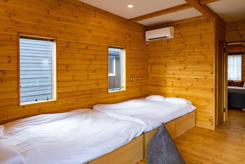 a bedroom with two beds in a wooden room at IZA近江舞子 in Minami-komatsu