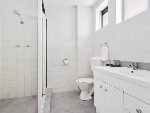 a white bathroom with a toilet and a sink at The Robert Towns in Townsville