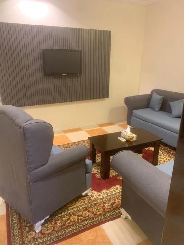a living room with two chairs and a tv at Orchid Tarif Serviced Apartments 1 شقق أوركيد طريف للشقق المخدومة 1 in Ţurayf