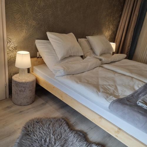 a bed with white pillows and a lamp in a room at Belvárosi Pihenőház in Békéscsaba