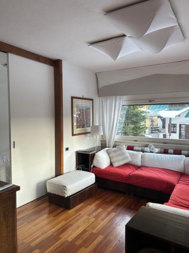 a living room with a red couch and a window at Casa Fiocco di Neve in Madonna di Campiglio