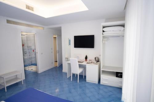 Habitación blanca con escritorio y TV. en Domus Sole en Sorrento