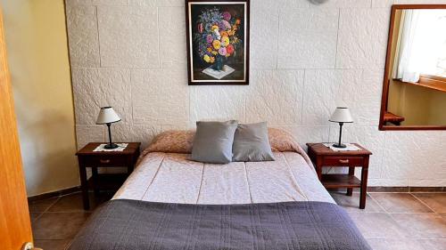 um quarto com uma cama com 2 mesas de cabeceira e 2 candeeiros em A orillas del lago, un espacio para tu tranquilidad em San Carlos de Bariloche