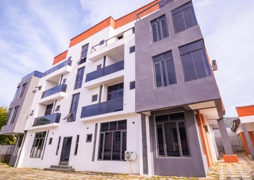 a white building with blue windows at Naya's Apartment: A Lush Ambience (Katampe, Abuja) in Abuja