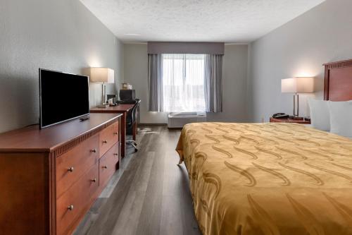 a hotel room with a bed and a flat screen tv at Quality Inn Near Fort Liberty formerly Ft Bragg in Fayetteville