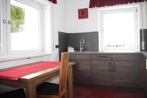 a kitchen with a wooden table and two windows at Erwachsenen Aparthotel Naturidyll - Der Wieserhof in Bad Füssing